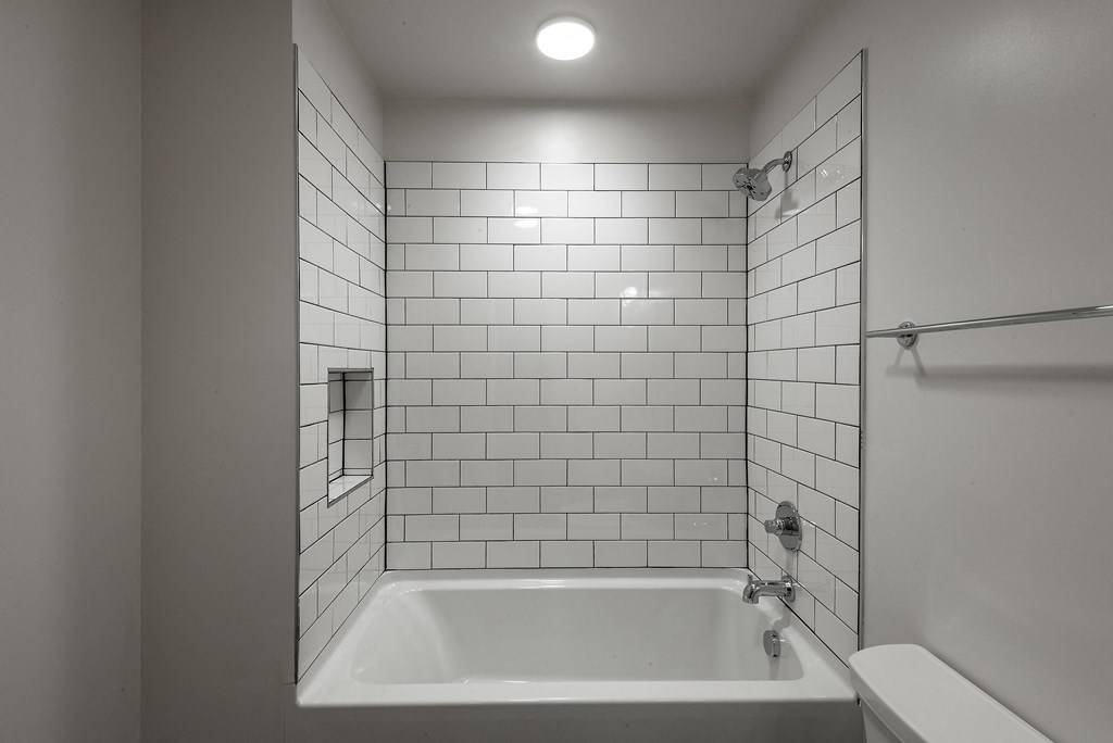 a bathroom with white tiles and a white bathtub